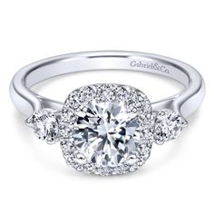 a white gold engagement ring with three round diamonds on the band and an oval center stone