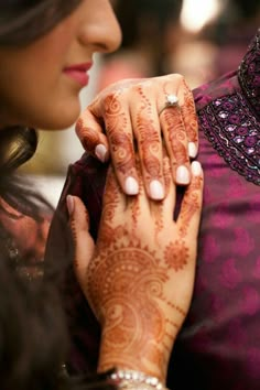 a close up of a person with henna on their hand holding another persons hand