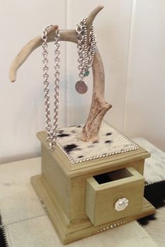 a jewelry box with a necklace hanging from it's side and a tree branch on top