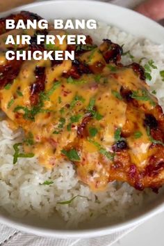 a white bowl filled with rice and chicken covered in sauce next to a hand holding a fork