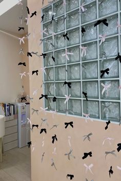 some birds are flying in the air near a wall with glass blocks and bottles on it