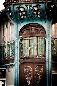 an old building with ornate iron work on the front door and side windows, painted teal