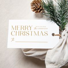 a white christmas card with a pine cone sitting on top of it next to a napkin