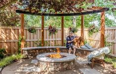 a woman sitting on a bench next to a fire pit in the middle of a yard