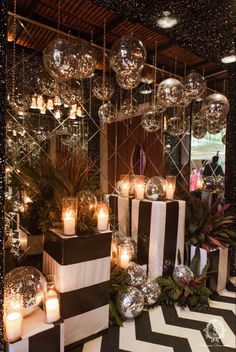 a room filled with black and white striped boxes covered in disco ball decorations next to candles