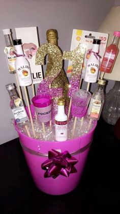 a pink bucket filled with lots of bottles and liquors on top of a table