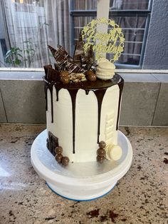 a white cake with chocolate drizzles and candies on top sitting on a counter