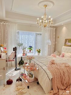 a bedroom with a bed, chandelier and table in front of the window