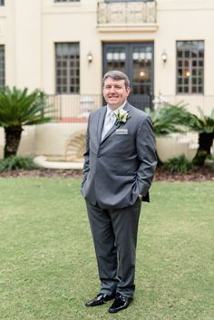 a man in a suit and tie standing in front of a building