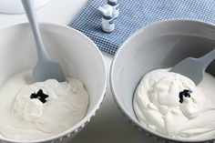 two white bowls filled with whipped cream on top of a table