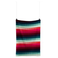 a multicolored blanket hanging from a clothes line on a hanger against a white background