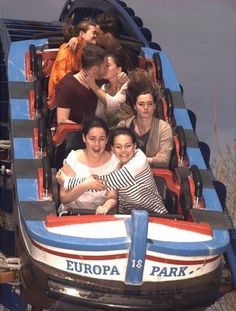 people are riding on a roller coaster at an amusement park, with one woman hugging the other