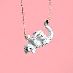 an elephant necklace is hanging from a gold chain on a pink background and it has two smaller elephants in the middle