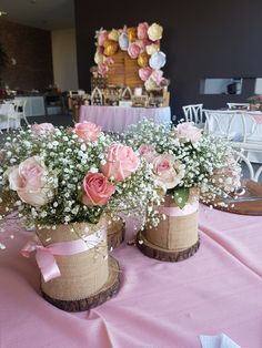 two vases filled with flowers on top of a pink table cloth covered tablecloth