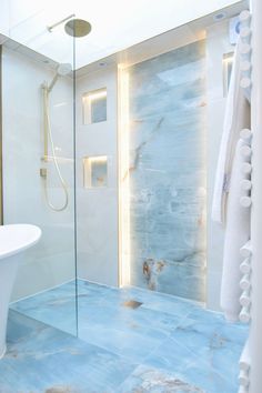 a bathroom with blue marble flooring and walls, along with a white bathtub