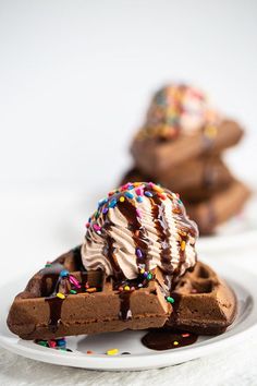 two pieces of chocolate cake on a plate with ice cream and sprinkles