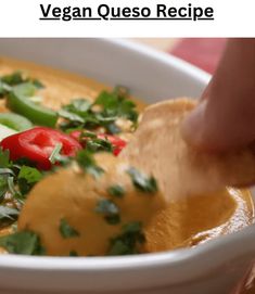 a person is dipping some food into a bowl with vegetables and sauce in it,