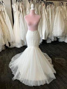 a white wedding dress on display in a bridal room with other dresses behind it