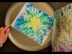 someone is painting something on a plate with silver foil and then it looks like an art project