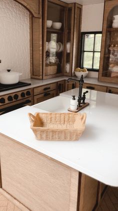 a kitchen with white counter tops and wooden cabinetry in the center, along with a basket on the island