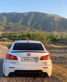 a white car parked on the side of a dirt road