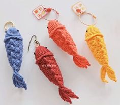 three crocheted fish keychains are shown in different colors and sizes, one is orange, the other is blue