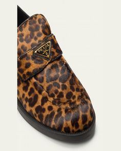 Prada leopardprint dyed calf hair (Italy) loafers with leather trim and triangle logo keeper.    1.00 in / 25 mm flat heel.    Round moc toe.    Notched vamp.    Leather lining.    Slipon style.    Rubber outsole.    Made in Italy. Leather Leopard Print Loafers With Flat Heel, Leopard Print Leather Loafers With Flat Heel, Hair Triangle, Travel Size Perfume, Evening Flats, Loafer Mules, Triangle Logo, Cleanser And Toner, Calf Hair