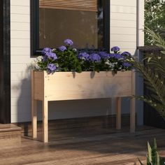 a wooden planter filled with purple flowers sitting on top of a wooden floor next to a window