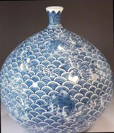 a large blue and white vase sitting on top of a table next to a wall