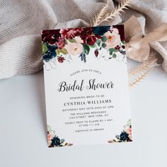 an elegant floral bridal shower card on top of a table with feathers and flowers