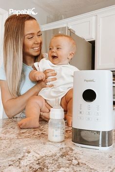 a woman holding a baby in her arms next to a bottle and an air humider