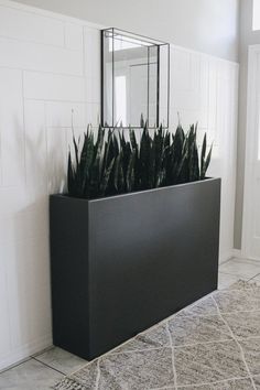 a black planter filled with lots of plants on top of a white tiled floor