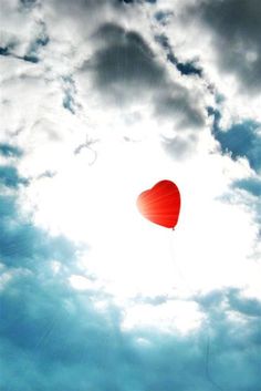 a red heart shaped kite flying in the sky