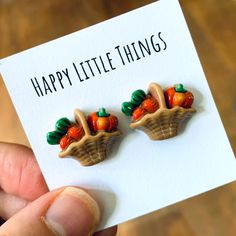 a person holding up a card with two little pumpkins on it and the words happy little things