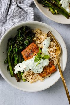 a white bowl filled with rice, broccoli and salmon