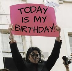 a woman holding up a sign that says today is my birthday