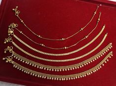 a red velvet box with gold jewelry on it and two rows of necklaces in the middle