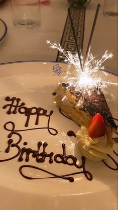 a piece of cake on a plate with the words happy birthday written in chocolate and sparklers