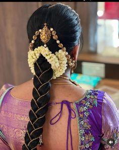 the back of a woman's head with braids and flowers in her hair