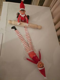 two elfs are sitting on top of a piece of paper and one is holding a baseball bat