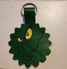 a green keychain with an angry grin face on it's front end