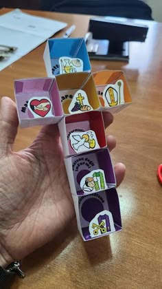 a person holding up some sort of colorful object on a wooden table next to scissors