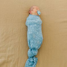 a sleeping baby wrapped in a blue blanket with a pacifier on it's head