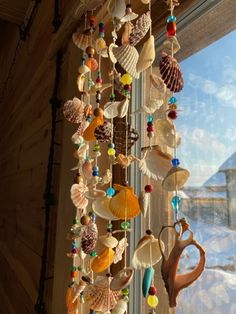 a wind chime with shells hanging from it's sides in front of a window