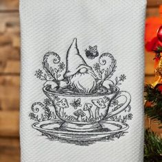 a teacup with an gnome on it is sitting next to a christmas tree