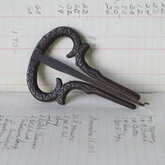 a pair of scissors sitting on top of a piece of paper with writing in the background