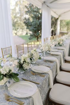 a long table with white flowers and place settings