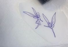 two small tinkerbells sitting on top of a white paper towel next to a black ink pen