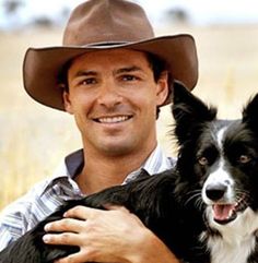 a man in a cowboy hat holding a black and white border collie dog on his chest