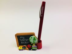 a pencil, eraser and school supplies sitting on a white surface with the words my teacher rocks written on it